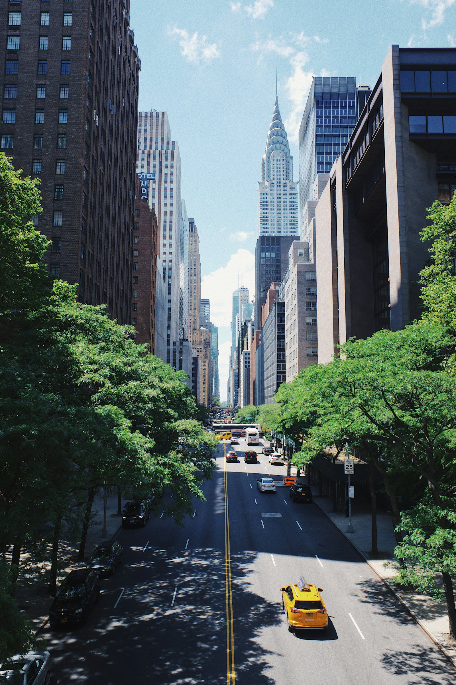 A yellow cab on a street between Manhattan towers